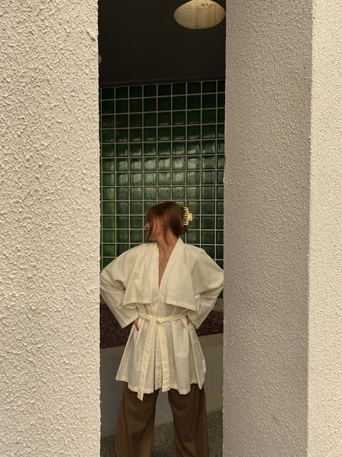 A woman in White Long Sleeve Blouse is Standing Beside Concrete Wall