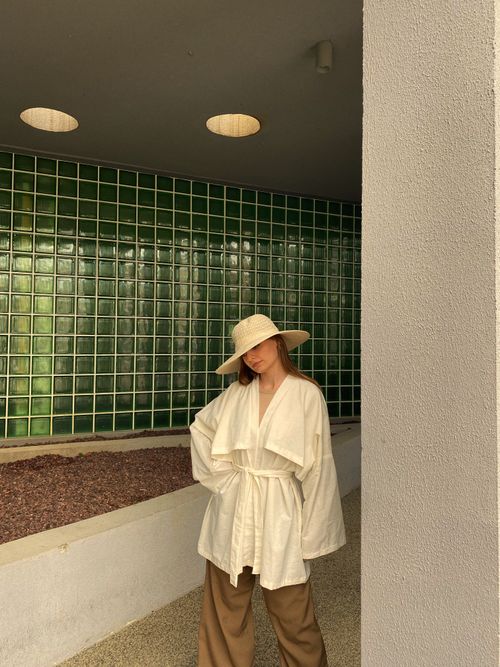 Free Stylish woman in minimalist outfit posing against modern architecture indoors. Stock Photo