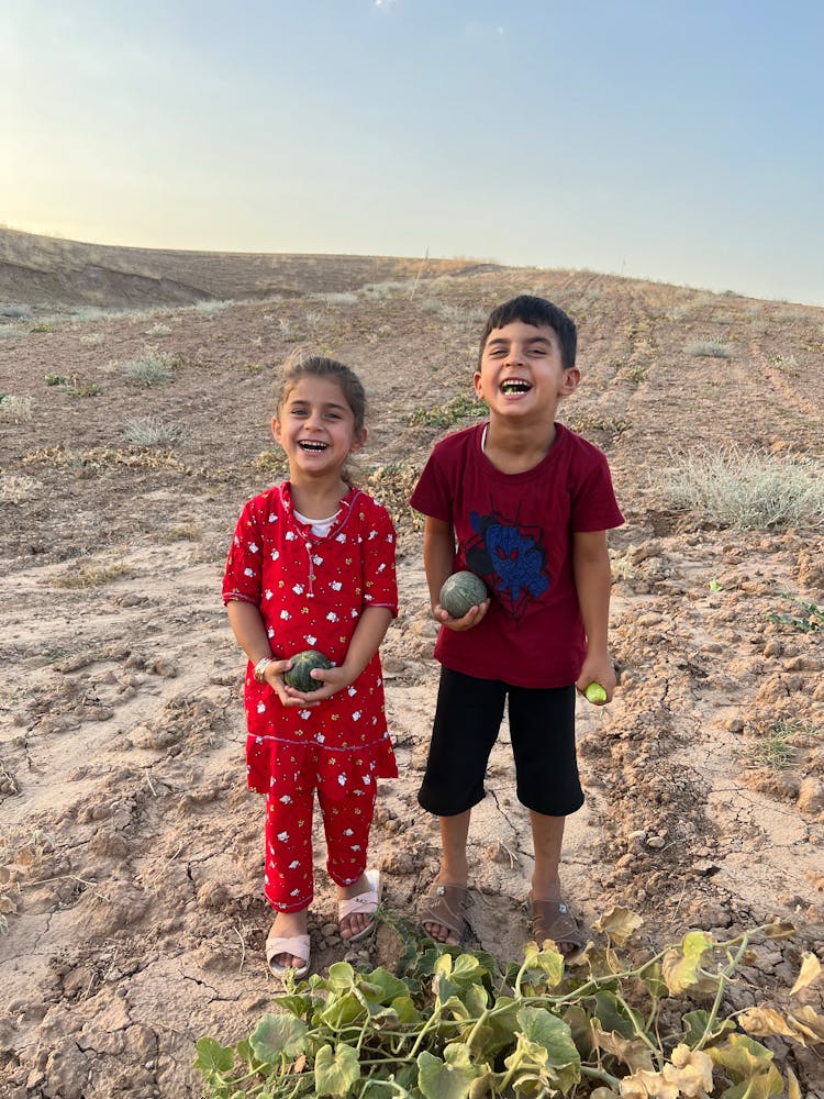 Smiling Children Standing In Arid Cropland