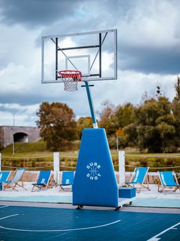 A vibrant outdoor basketball court with a hoop and wooden chairs during fall.