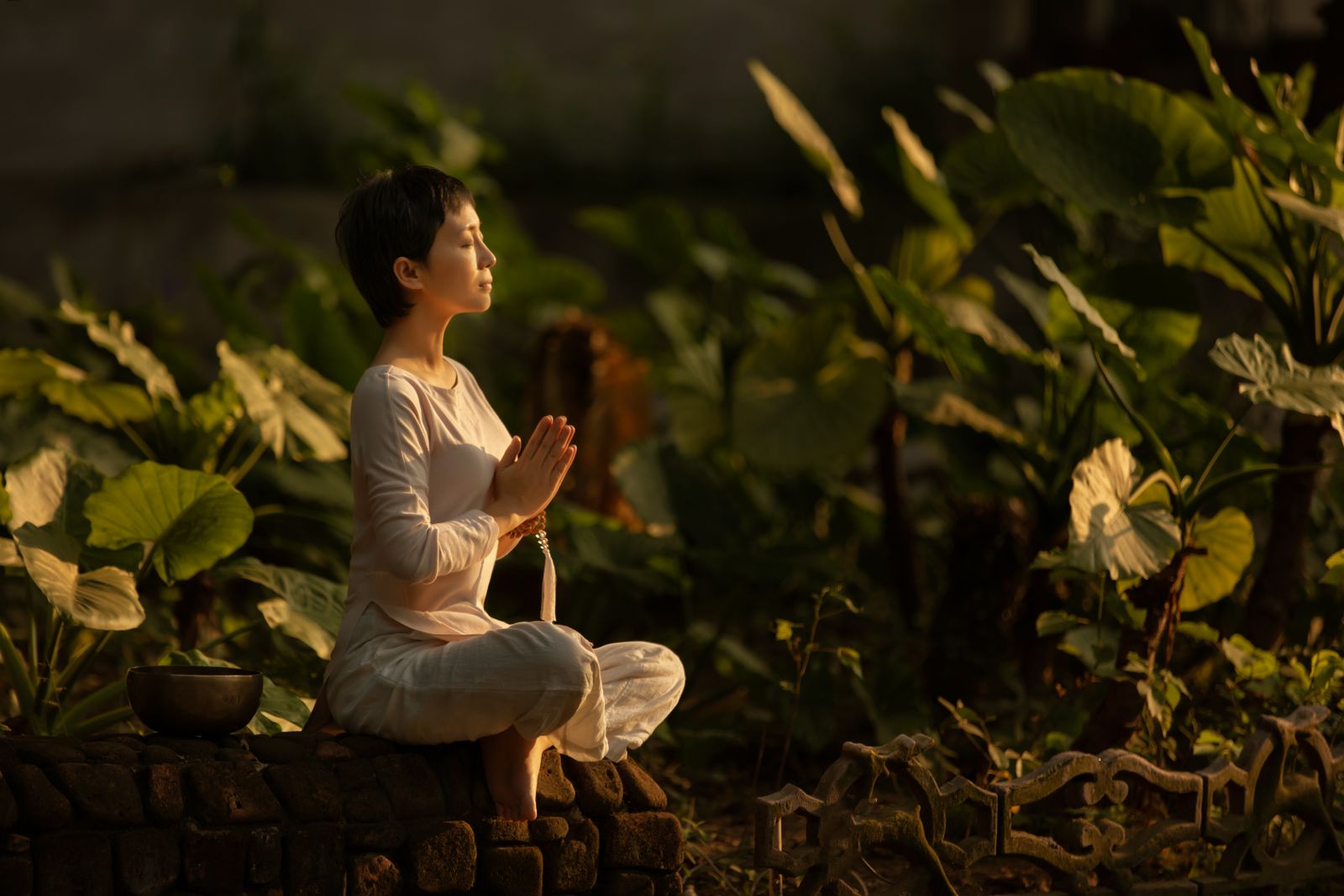 Woman meditating quietly in a garden setting, representing the inner reflection required to practice satya truthfulness