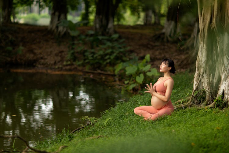 Pregnant Woman Doing Relaxation Exercise By The Lake