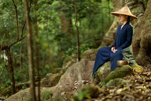 Woman in Blue Long Sleeve Dress Sitting on Tree Root