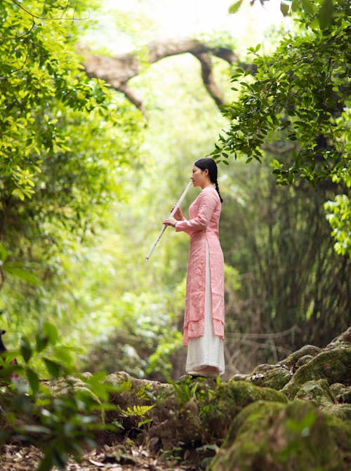 A Woman in Pink and White Dress Standing on Rock