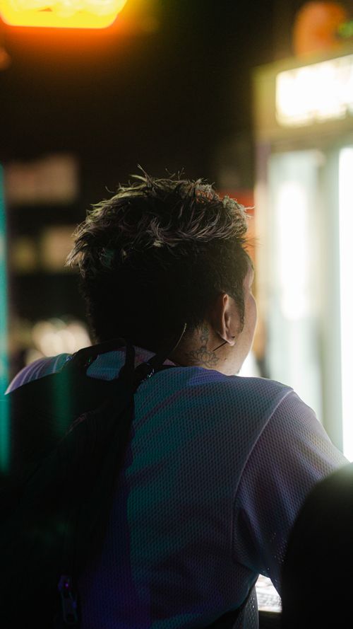Free A person with a backpack in a lively club environment, illuminated by colorful lights. Stock Photo