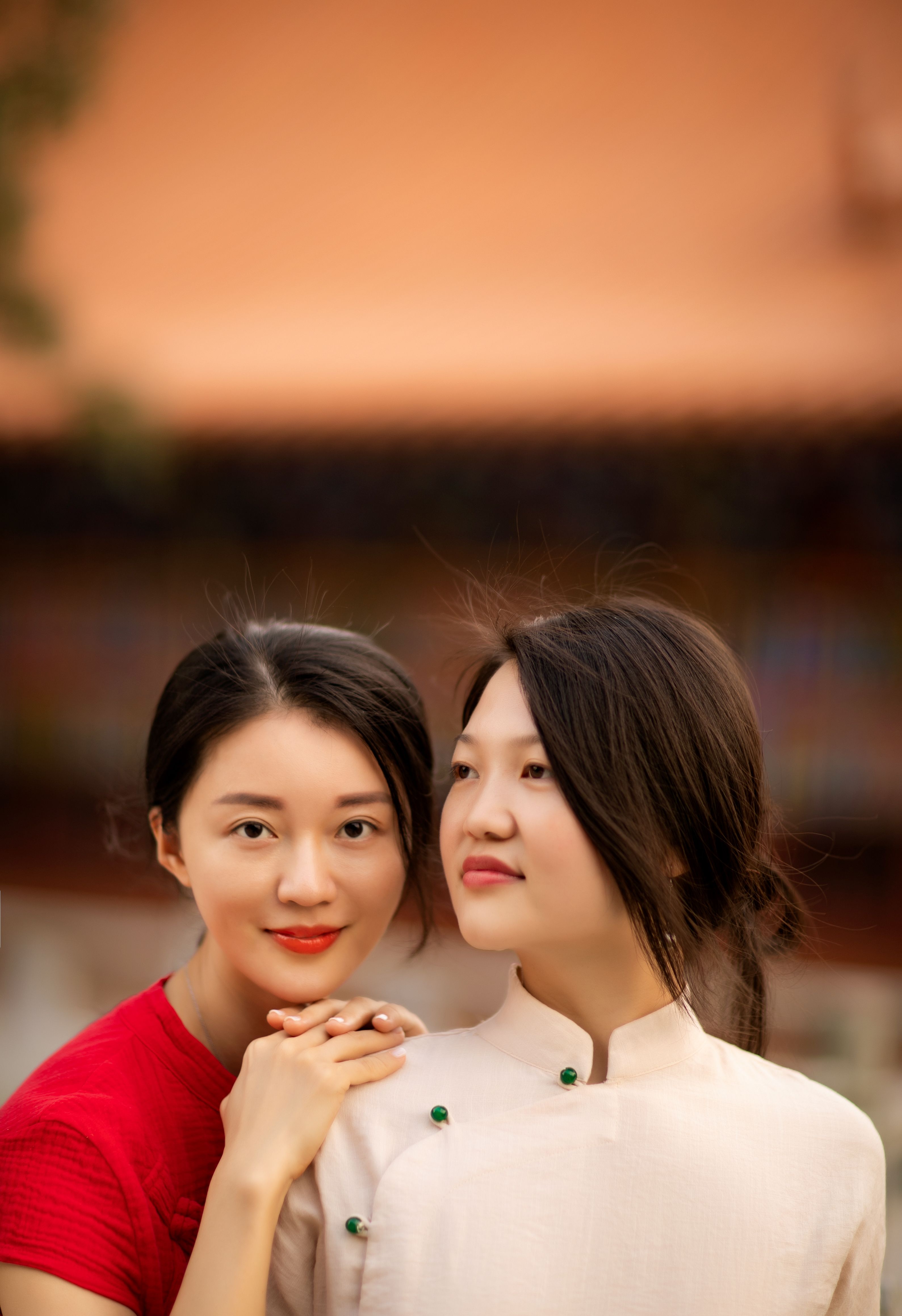 A close-up portrait of two smiling women in traditional Chinese clothing, exuding warmth and friendship.
