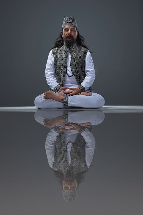 Man Wearing Traditional Clothing Meditating and Reflecting in the Floor