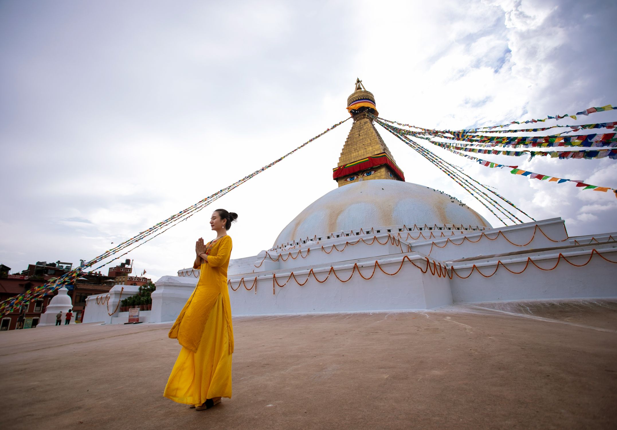 A woman in a yellow dress prays near the Boudhanath Stupa in Kathmandu, Nepal.