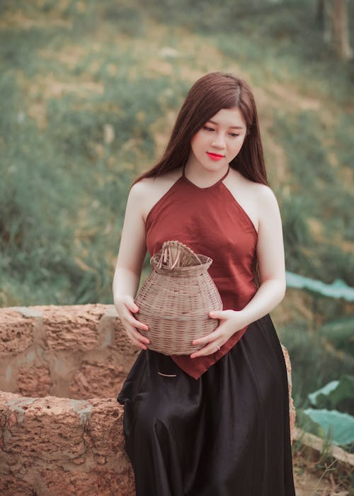 Free Woman in Red Top Sitting on a Water Well Stock Photo