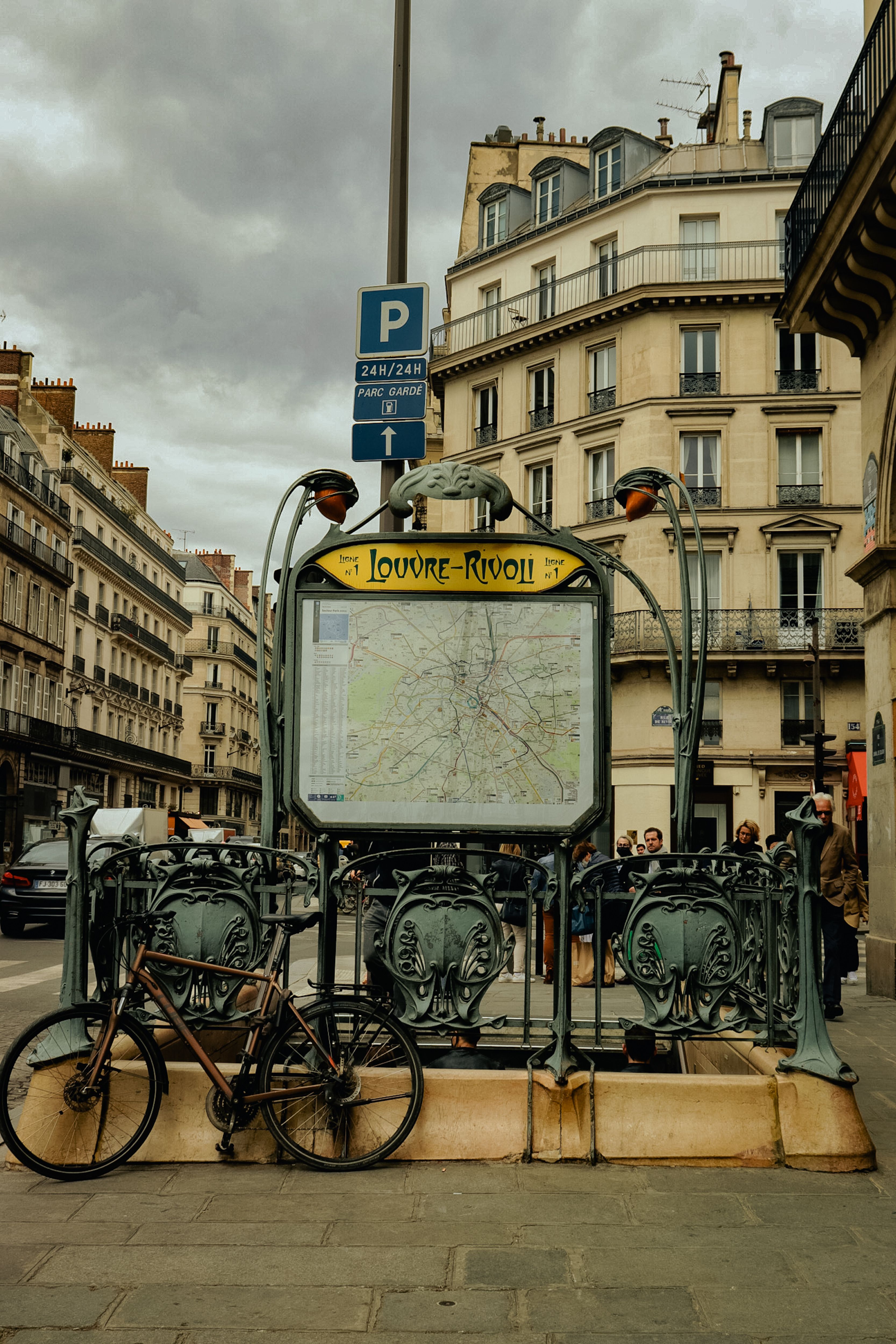 Paris street view featuring Louvre-Rivoli metro entrance under cloudy skies.