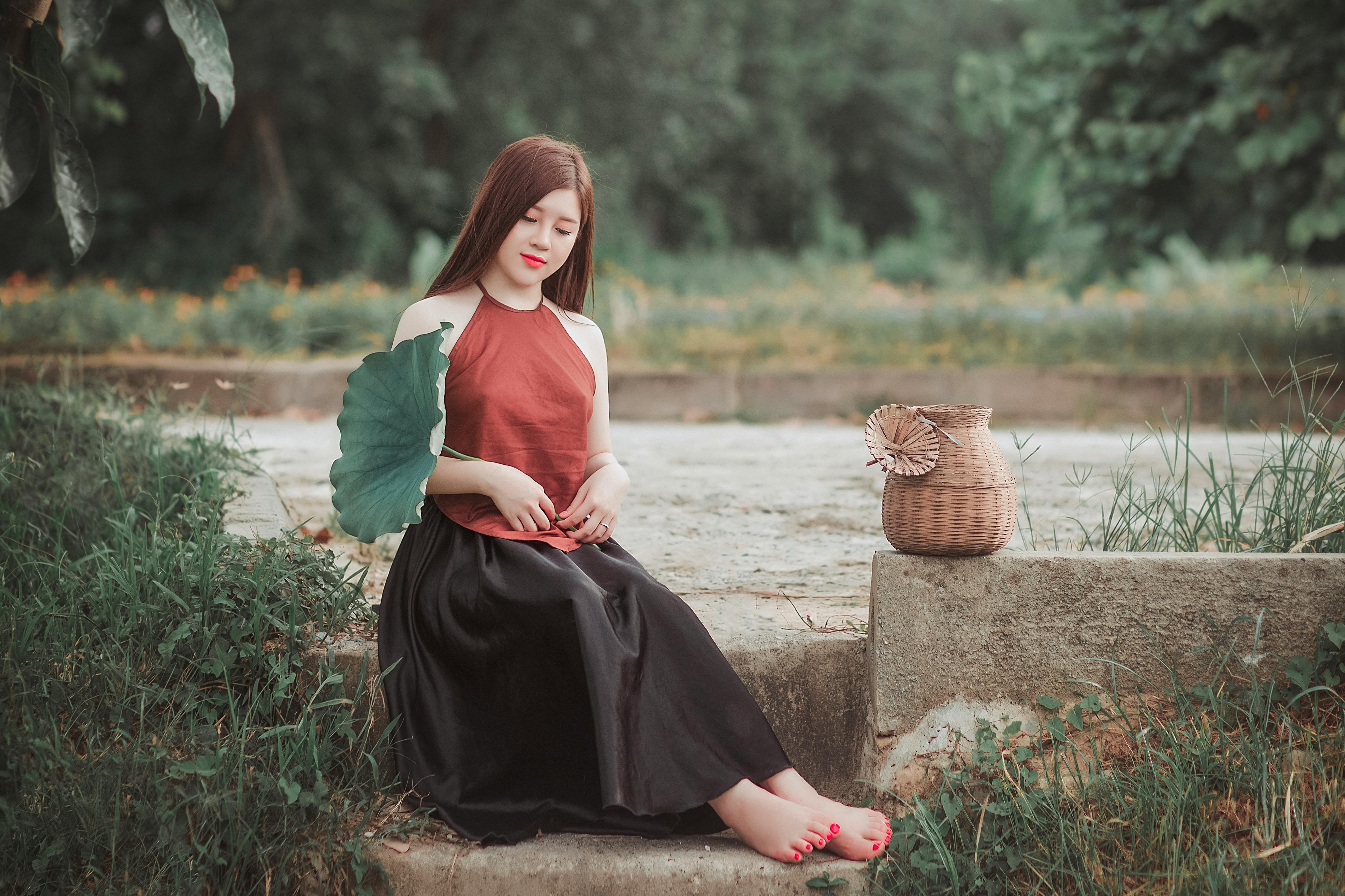 一位亚洲女性在大自然中优雅地手持一片树叶和一个柳条篮，宁静而安详