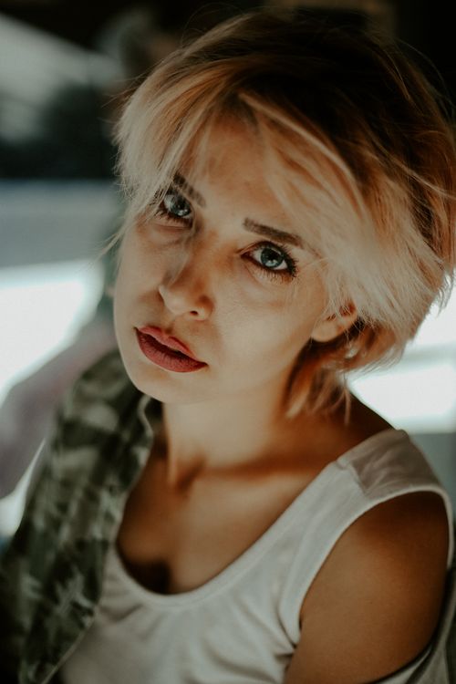 Free Elegant close-up portrait of a fashionable woman with blonde hair wearing a white tank top. Stock Photo