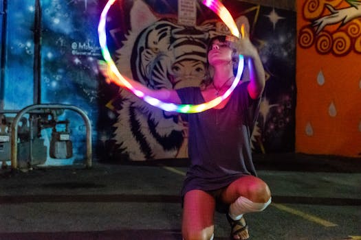 一名女子在充满活力的街头艺术背景下，用发光的铁环表演，为夜色增添了活力