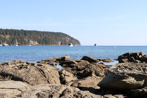 Free Stunning coastal landscape with boats on a sunny day, showcasing rocky shore and blue ocean. Stock Photo