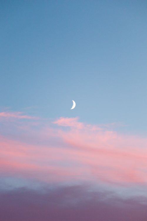 Free A delicate crescent moon set against a vibrant pastel sky, creating a tranquil evening scene. Stock Photo