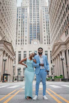 Stylish couple in formal attire posing in a modern city street.