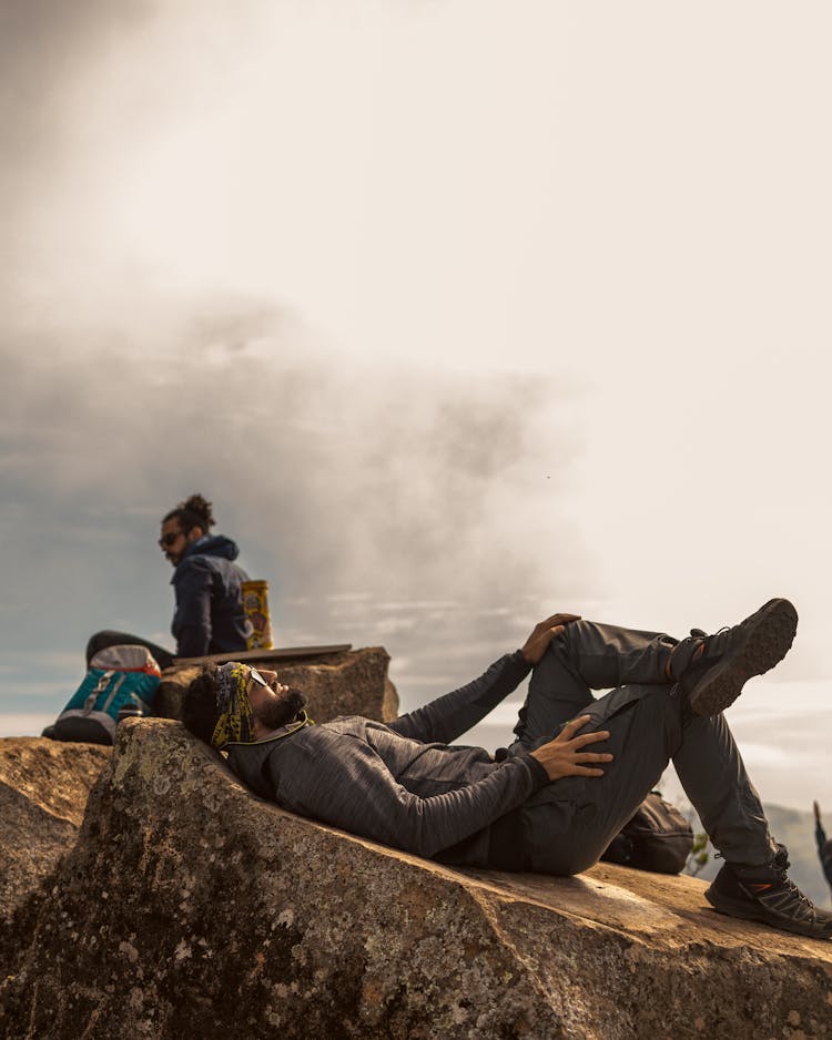 Men Wearing Hoodies Relaxing On Stone Boulder Outdoor Photo