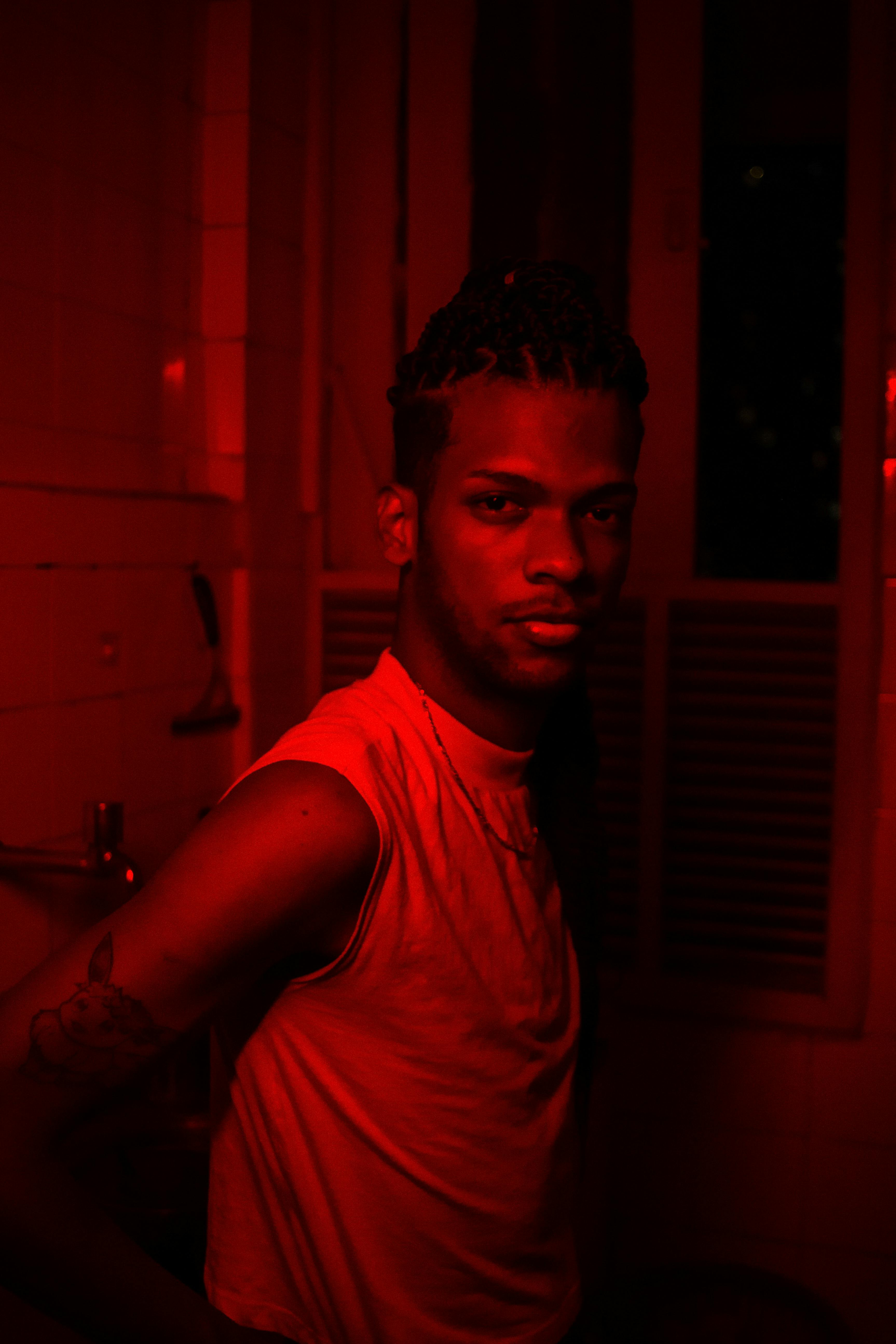 Dramatic portrait of a man in a red-lit room, capturing a bold mood.