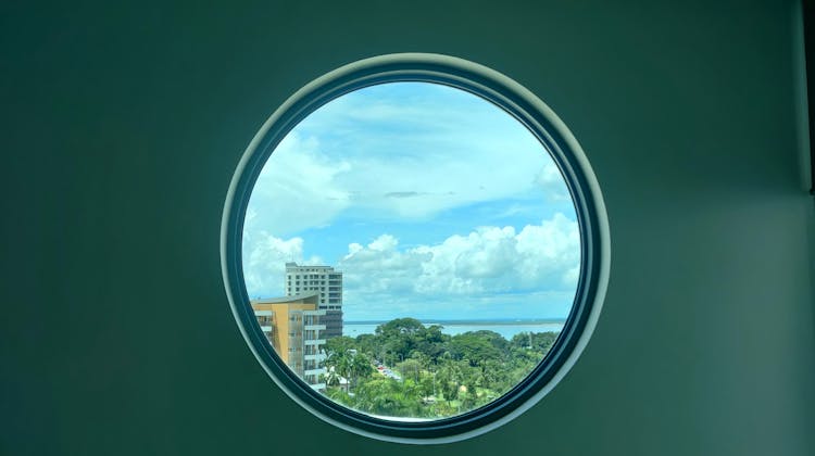 View Of Trees And Buildings From A Round Window