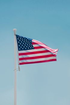 A vibrant American flag waves against a clear blue sky in Washington, DC.