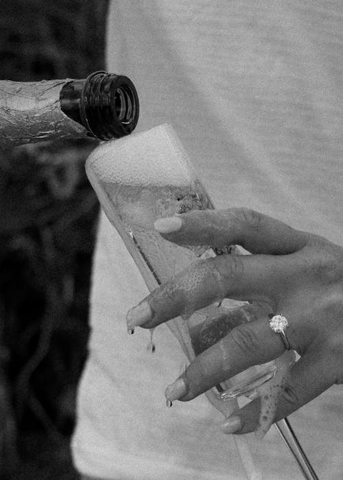 Grayscale Photo of Person Pouring Wine on a Wine Glass