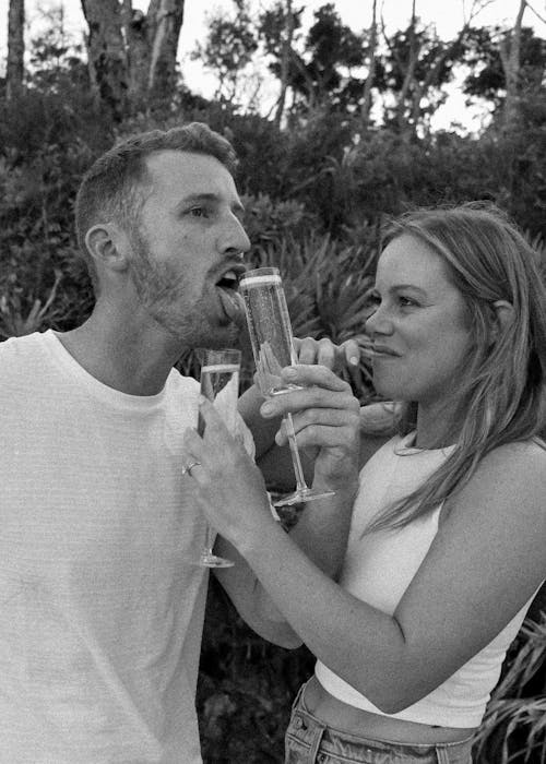 Grayscale Photo of a Romantic Couple Holding Glasses of Wine