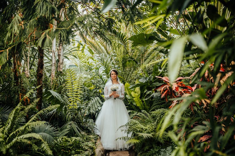 Bride In Wedding Dress Posing In Tropical Garden