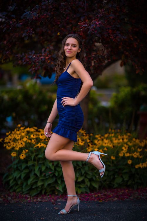 Free Woman posing elegantly in a blue dress amidst vibrant flowers. Stock Photo