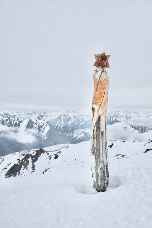 Free Wooden sculpture on snowy mountain with panoramic alpine view. Stock Photo
