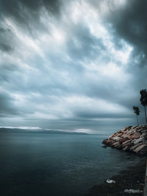 Free Dramatic overcast ocean scene with rocky shoreline and moody sky. Stock Photo