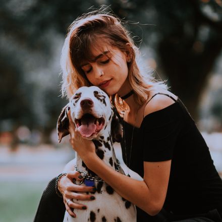 Woman holding her dalmatian, photo by Matheus Bertelli on Pexels