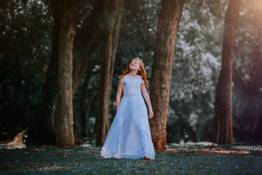 A young girl in a white gown enjoys the magical atmosphere of a sunlit forest.