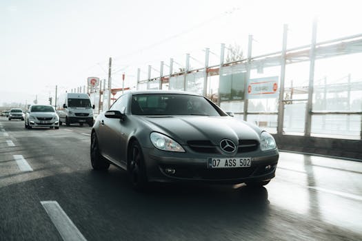 A sleek black Mercedes Benz cruising on a busy city road during the day.