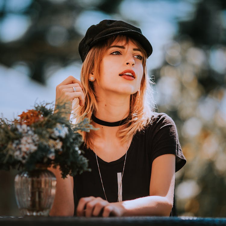 Young Woman Sitting At A Table Outdoors 