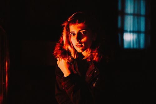 Free Young woman in a winter jacket, dramatically lit at night, indoors. Stock Photo