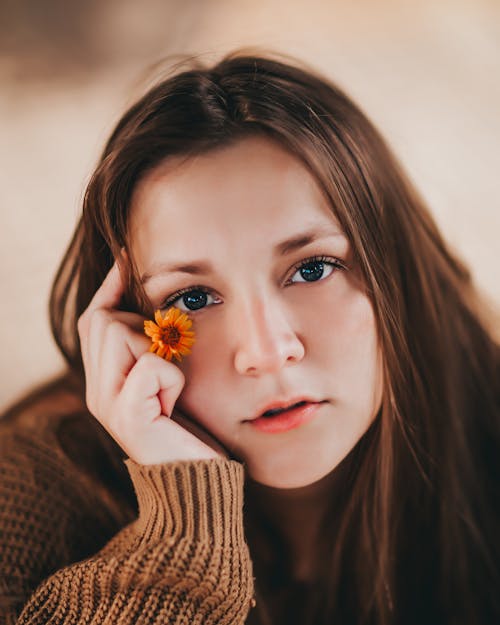 Young Woman Holding a Little Yellow Flower Next to Her Face 