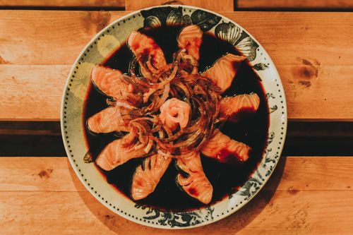 Free Top view of salmon sashimi on ceramic plate with soy sauce and onions, perfect for seafood lovers. Stock Photo