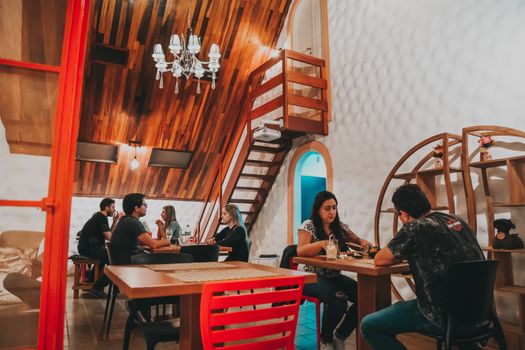 A warm and inviting cafe with people enjoying their meals and engaging in conversation indoors.