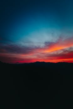 A breathtaking sunset with vibrant red and orange hues over silhouetted mountains. Perfect for backgrounds and wallpapers.