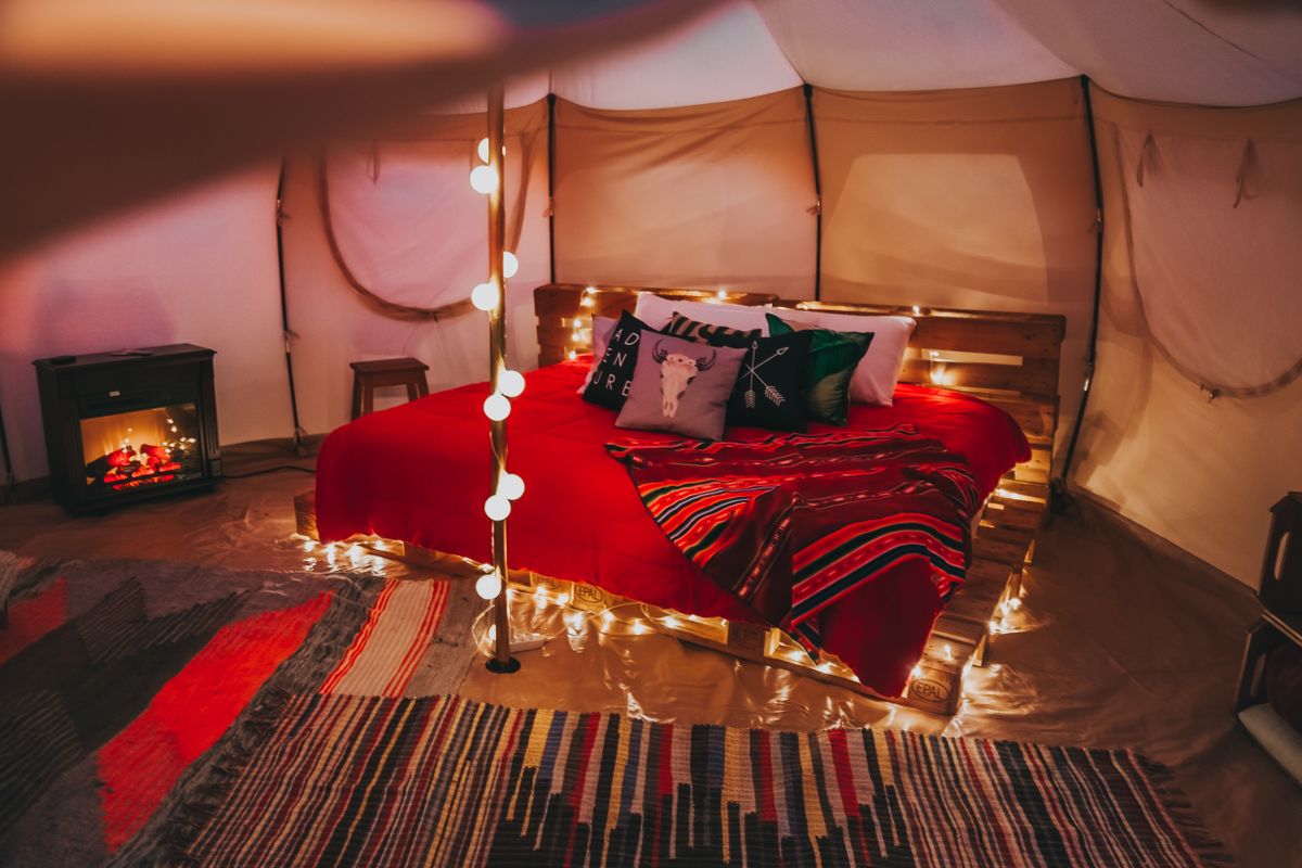 Interno di una tenda glamping con luci calde e letto accogliente