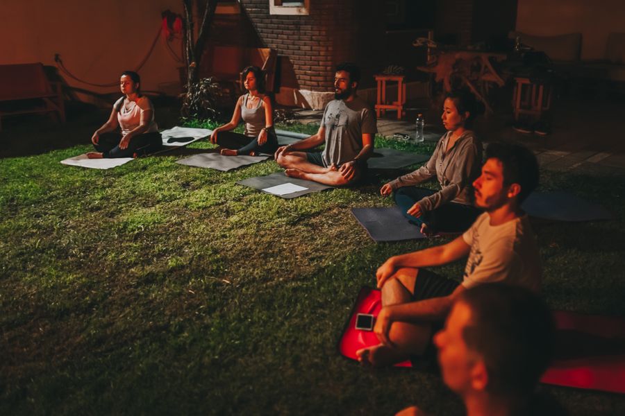 A group meditating together at dusk on a quiet lawn