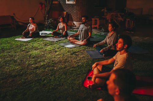 Free A diverse group meditating outdoors on yoga mats during evening time. Stock Photo