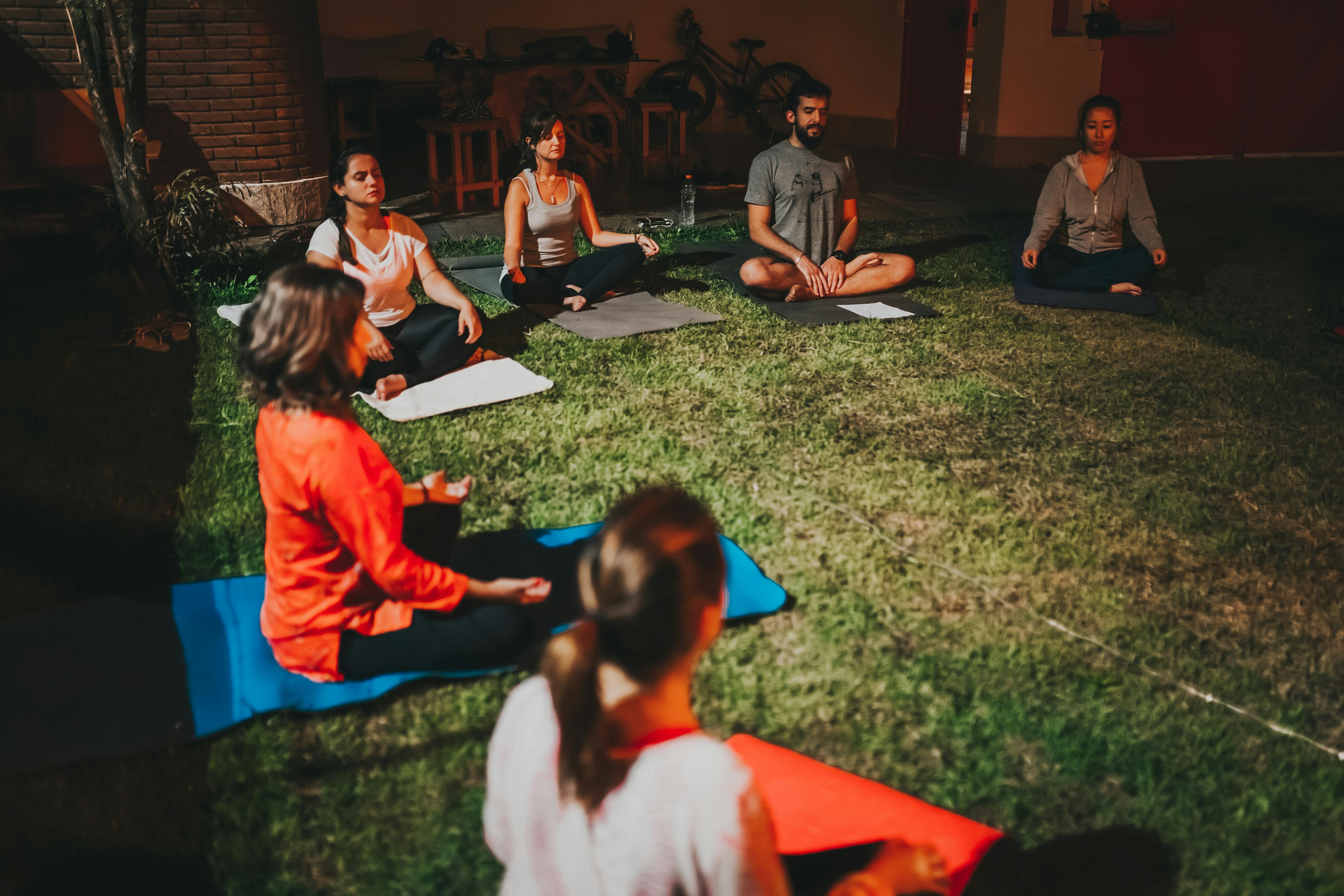 A group practicing meditation and yoga outdoors at night, fostering relaxation and mindfulness.