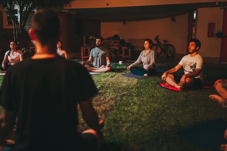 Group Of People Sitting On Green Grass Field Meditating