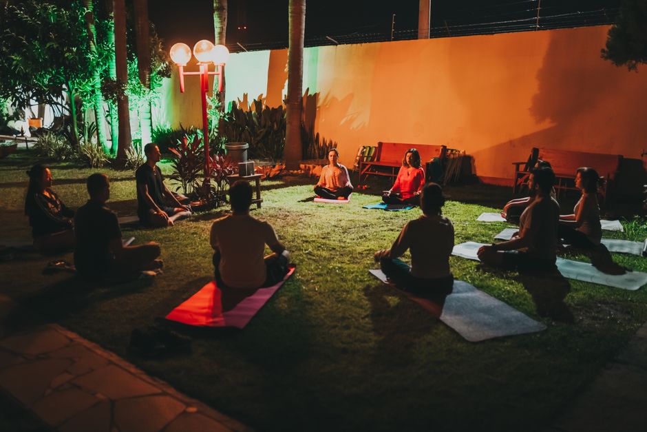 Como Criar um Espaço Aconchegante para Meditação em Casa 2 Group meditating in an outdoor yoga session at night, serene and peaceful atmosphere.