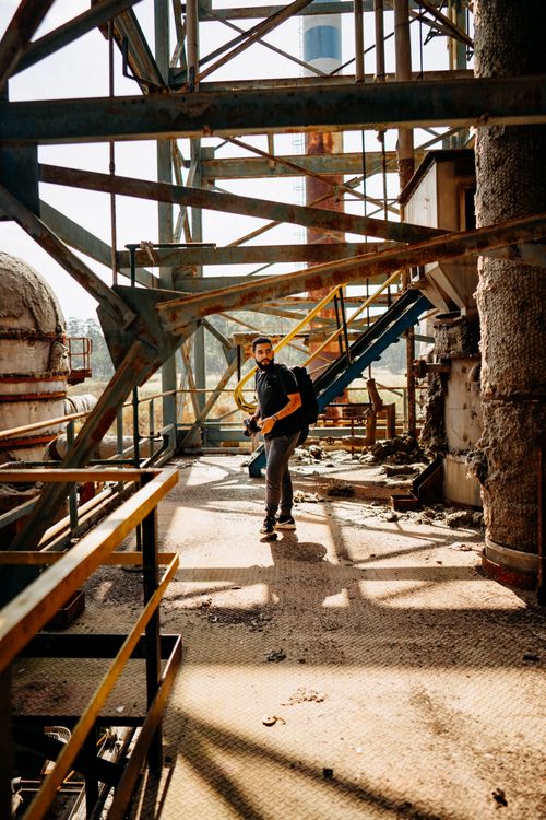Free A man explores an abandoned industrial site with rusty scaffolding in daylight. Stock Photo