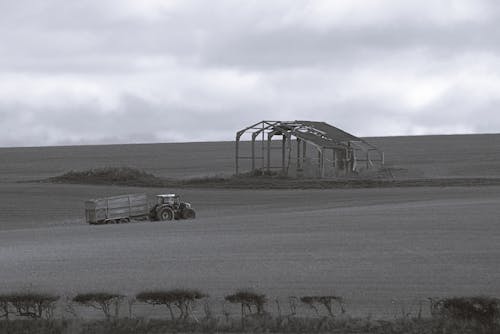Grayscale Photo of a Tractor on a Field