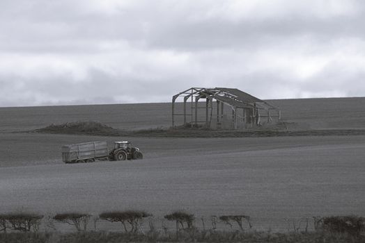 Serene rural scene in Ringstead, England with a tractor and barn.