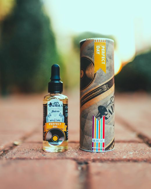 Vibrant e-juice dropper bottle and packaging in a warm outdoor setting. Ideal for product photography.