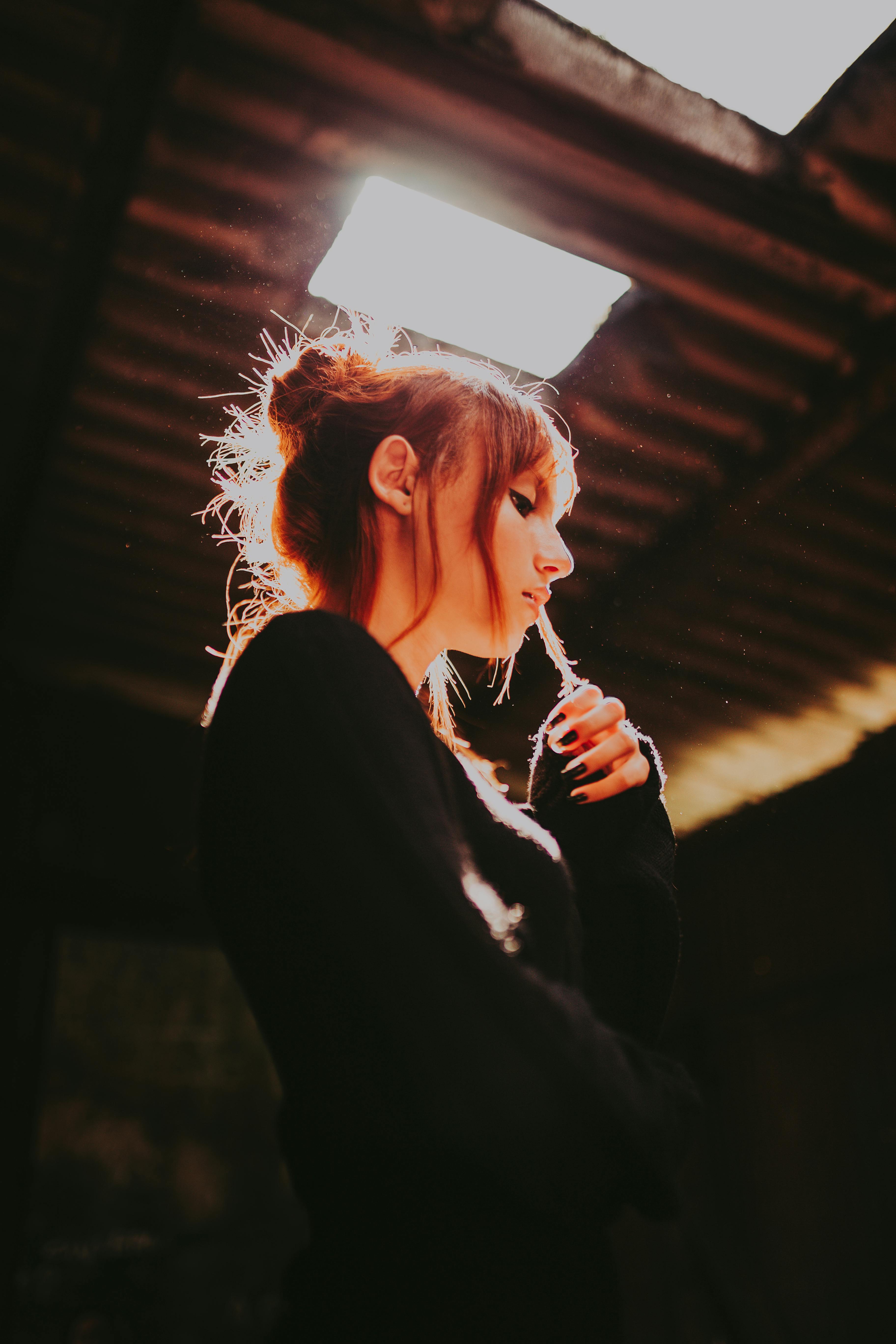 A captivating portrait of a young woman backlit in an underground space, creating a dramatic mood.